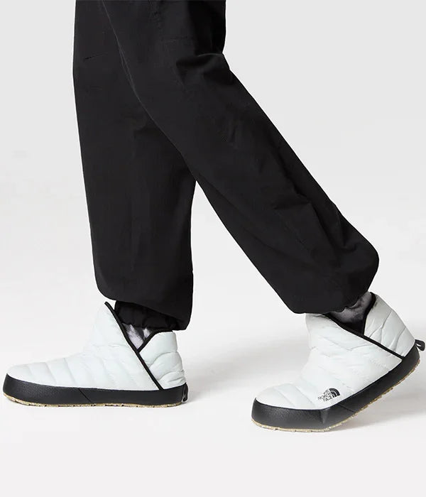 נעלי בית לבנות The North Face עם סוליה שחורה, נלבשות על רגליים עם מכנסיים שחורים, CHOZEN