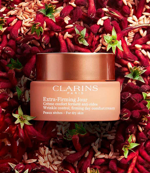 קרם פנים קלרינס Extra-Firming Jour למראה מוצק, מוצג על רקע פרחים אדומים, יבוא קבוצת אלפא