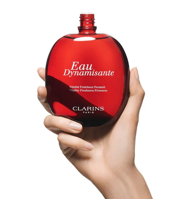 בקבוק בושם קלרינס Clarins Eau Dynamisante אדום מוחזק ביד, צילום מוצר באתר CHOZEN