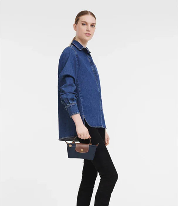 אישה עם חולצת ג'ינס כחולה, מכנסיים שחורים ותיק יד קטן, צילום אופנה ל-CHOZEN