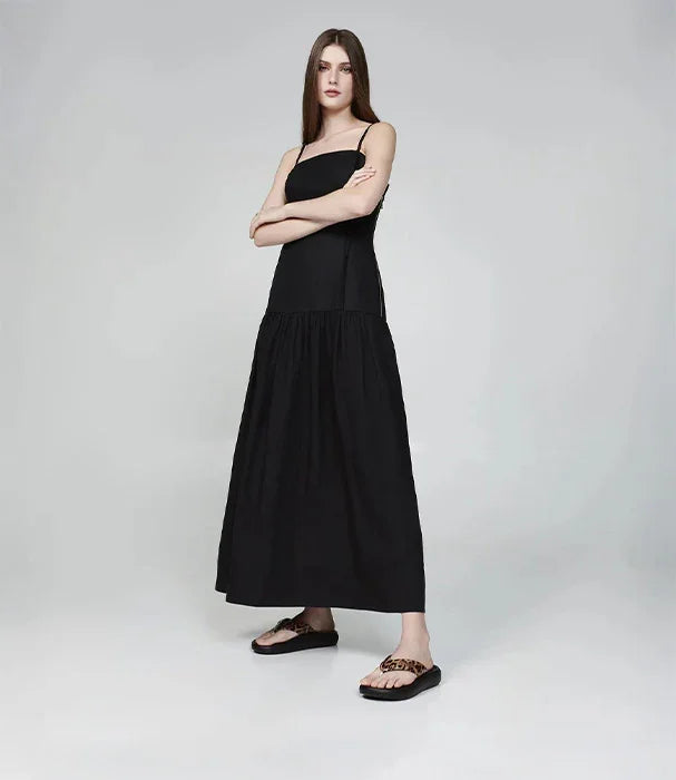 אישה לבושה בשמלה שחורה ארוכה ונעלי כפכף בעיצוב מודרני, צילום לאתר CHOZEN