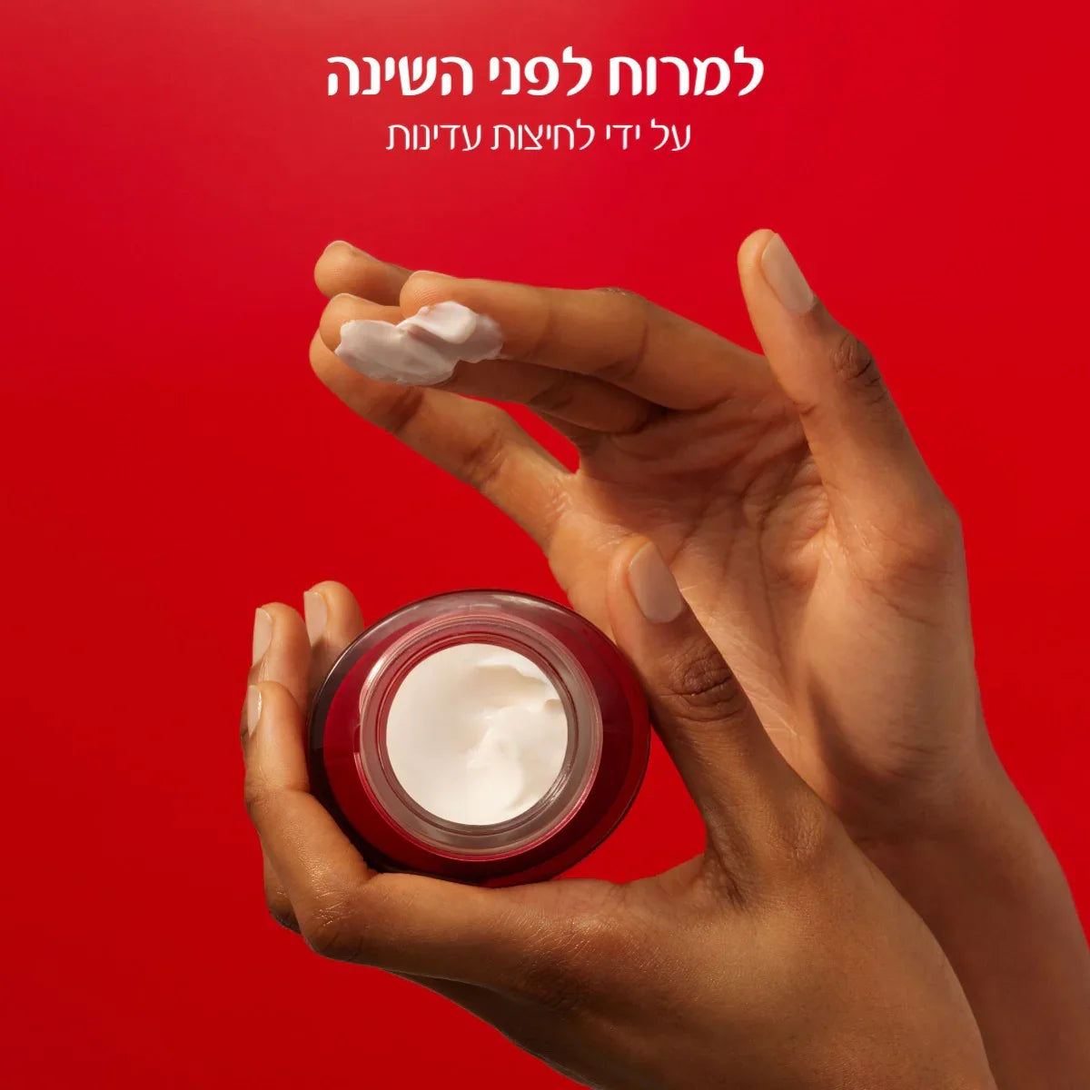 ידיים מחזיקות קרם לחות בצנצנת אדומה על רקע אדום, מוצר טיפוח CHOZEN