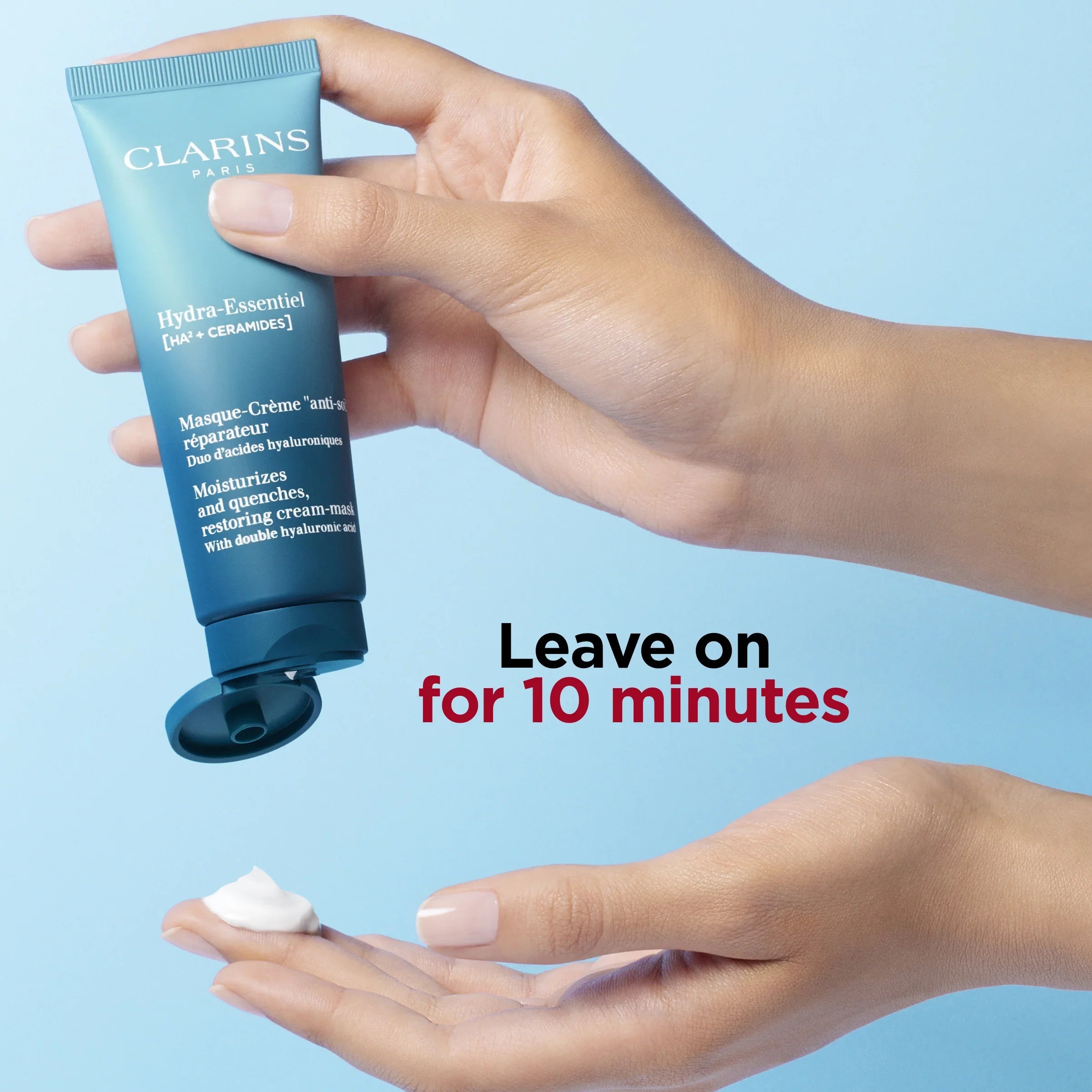 יד מחזיקה מסכת לחות Clarins Hydra-Essentiel על רקע תכלת, קרם מונח בכף היד