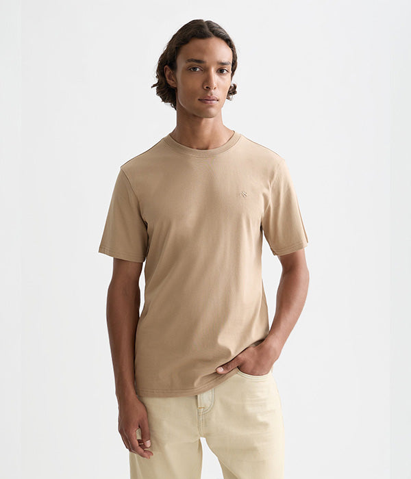 גבר לובש חולצת טי בז׳ אופנתית מבית CHOZEN על רקע לבן, קיץ, בגדי מותגים לגברים