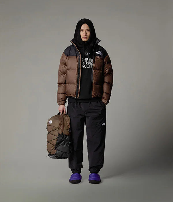 דוגמן לובש בגדי THE NORTH FACE, מעיל פוך חום ומחזיק תיק חום, בסטייל אורבני של CHOZEN