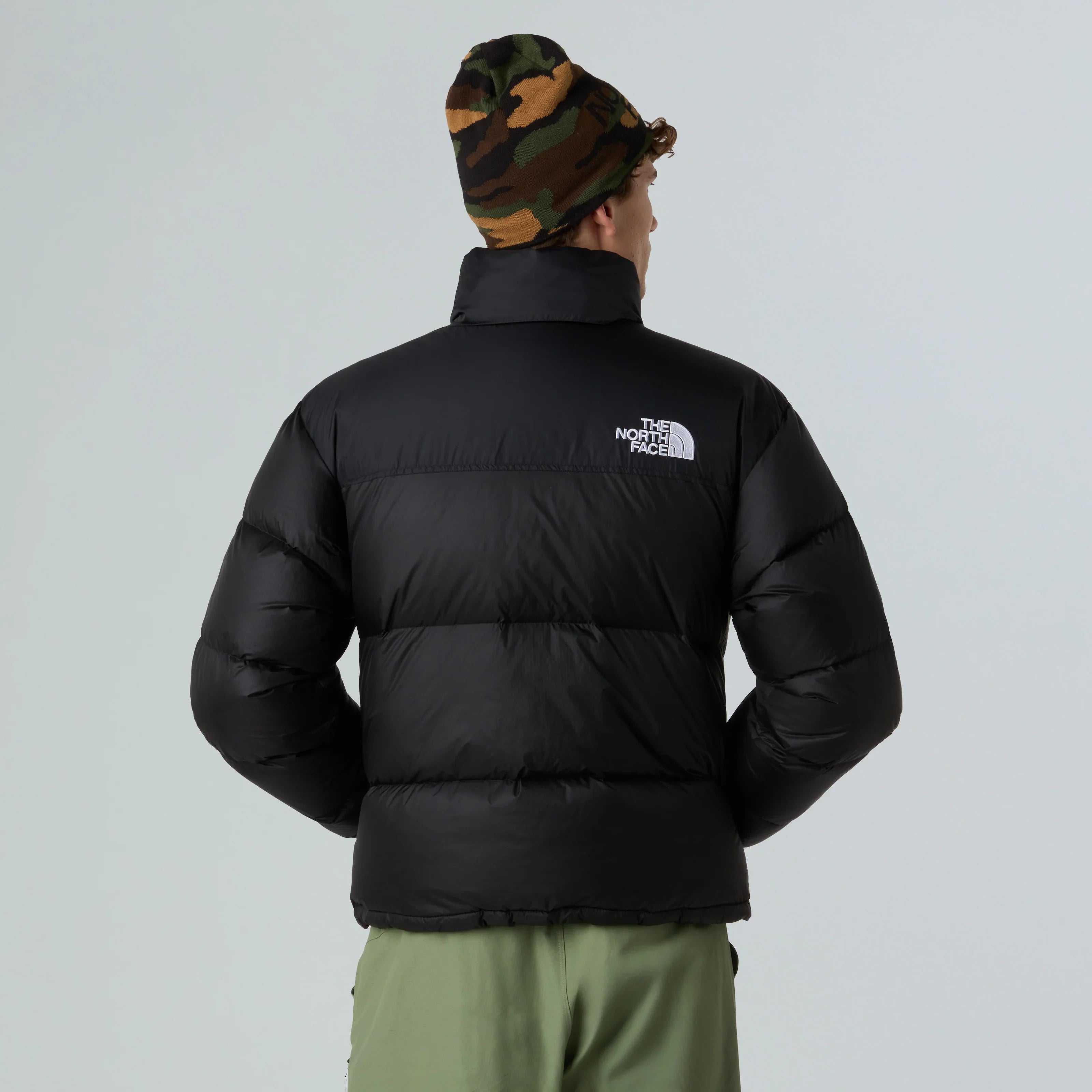 גבר עם מעיל פוך שחור של The North Face וכובע צמר צבאי, צילום מאחור, CHOZEN מותגים מובילים