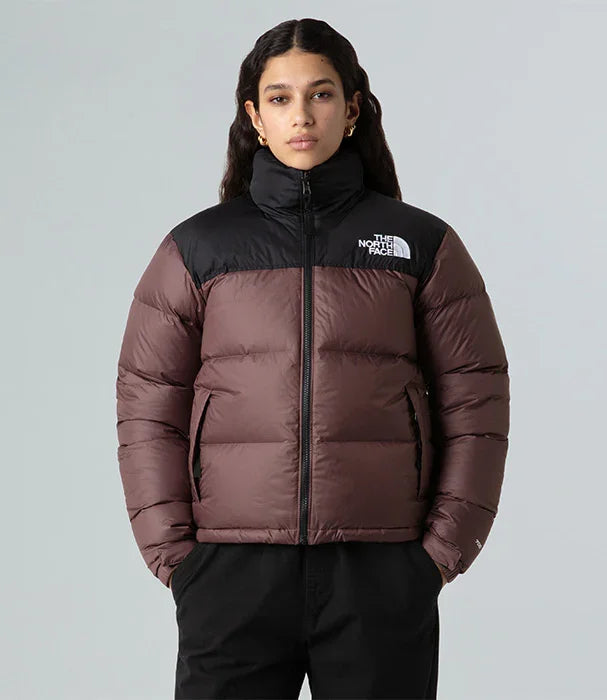 אישה לובשת מעיל פוך חום שחור של The North Face רקע אפור CHOZEN מותגים מובילים