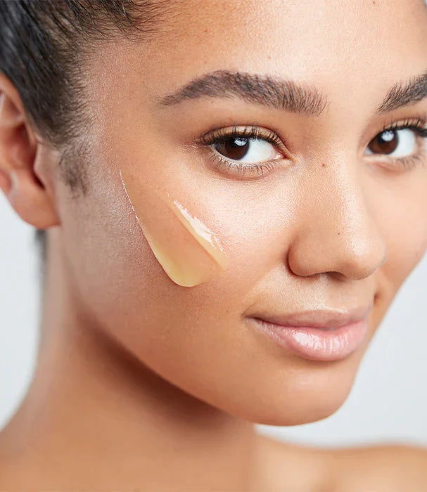 אישה עם עור זוהר מורחת סרום טיפוח על הלחי, קוסמטיקה יוקרתית מ-CHOZEN