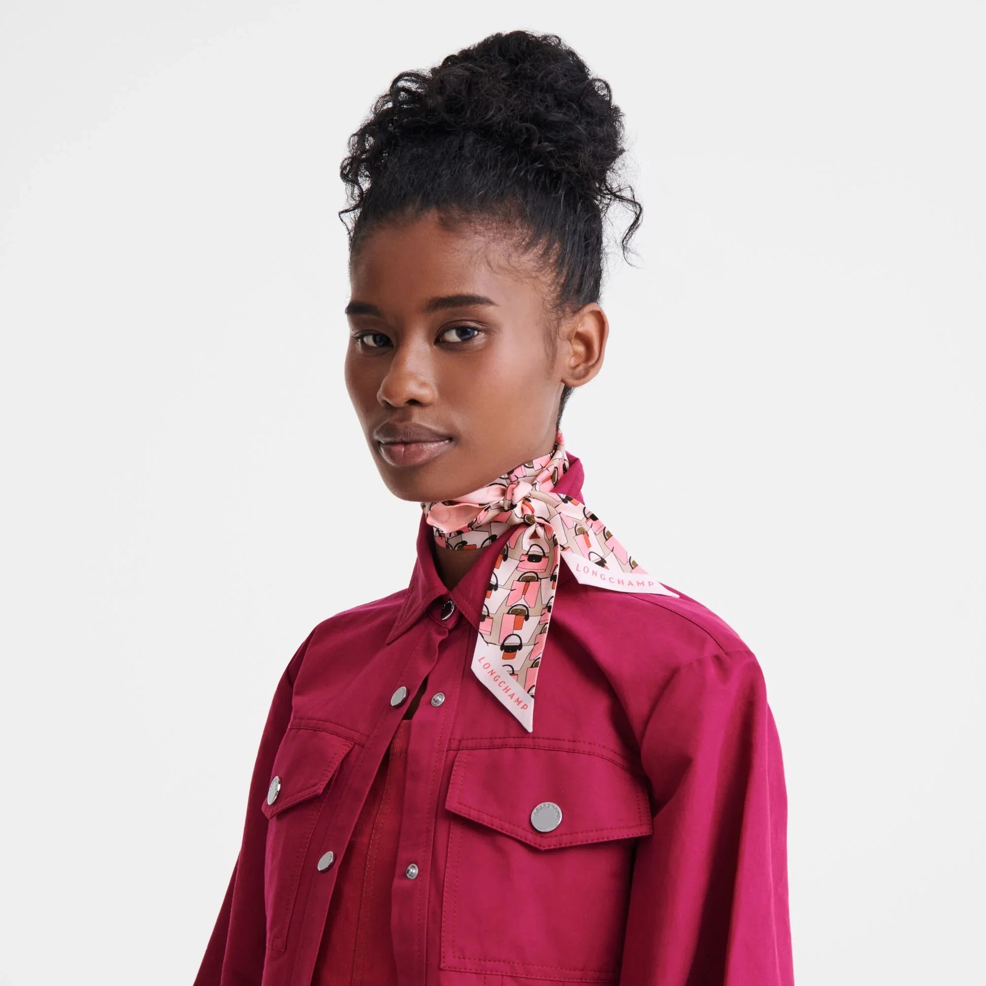 אישה לובשת חולצה ורודה ועונדת צעיף משי ורוד של LONGCHAMP, צילום אופנה CHOZEN