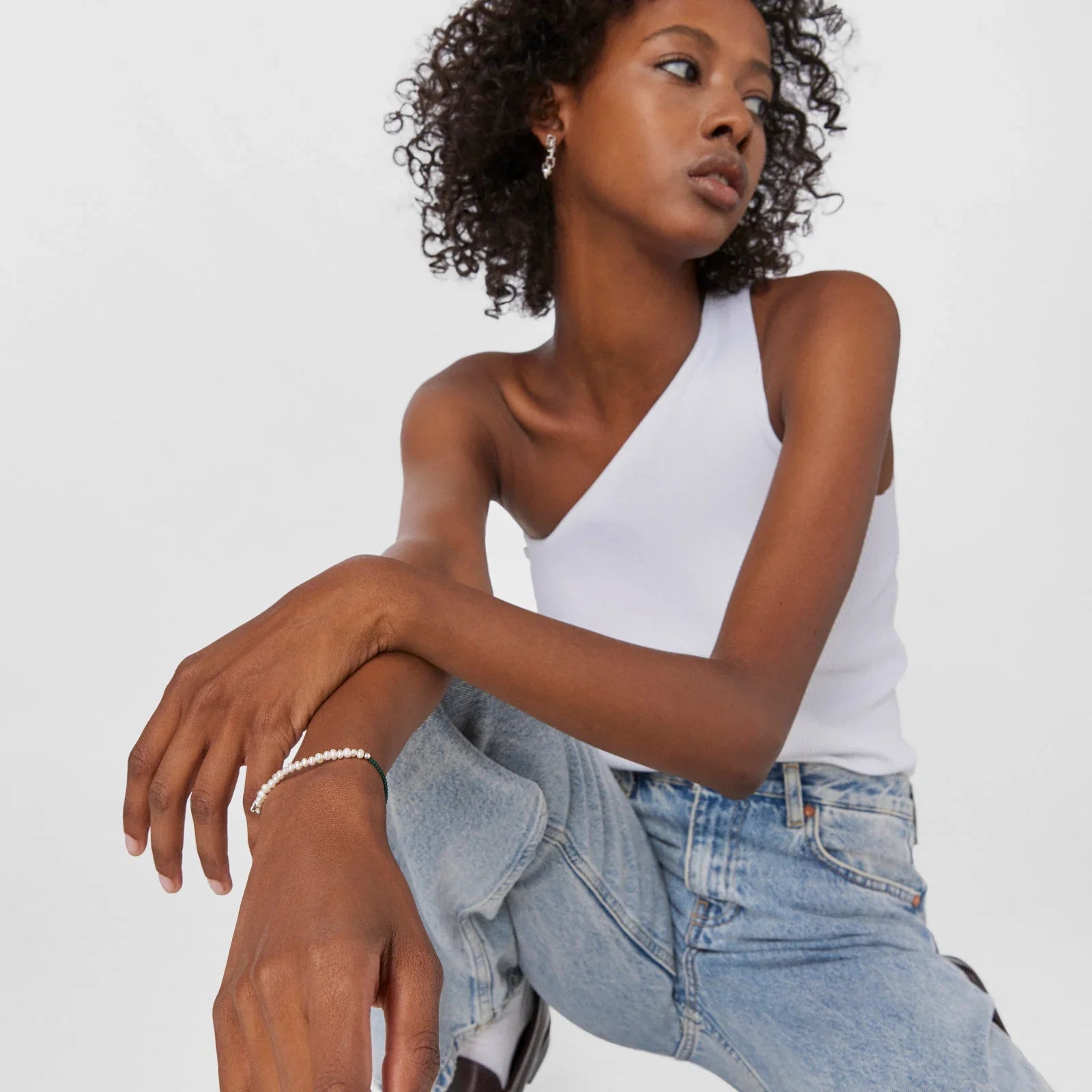 אישה עם גופיה לבנה כתף אחת, ג'ינס וצמיד פנינים, צילומי אופנה של CHOZEN