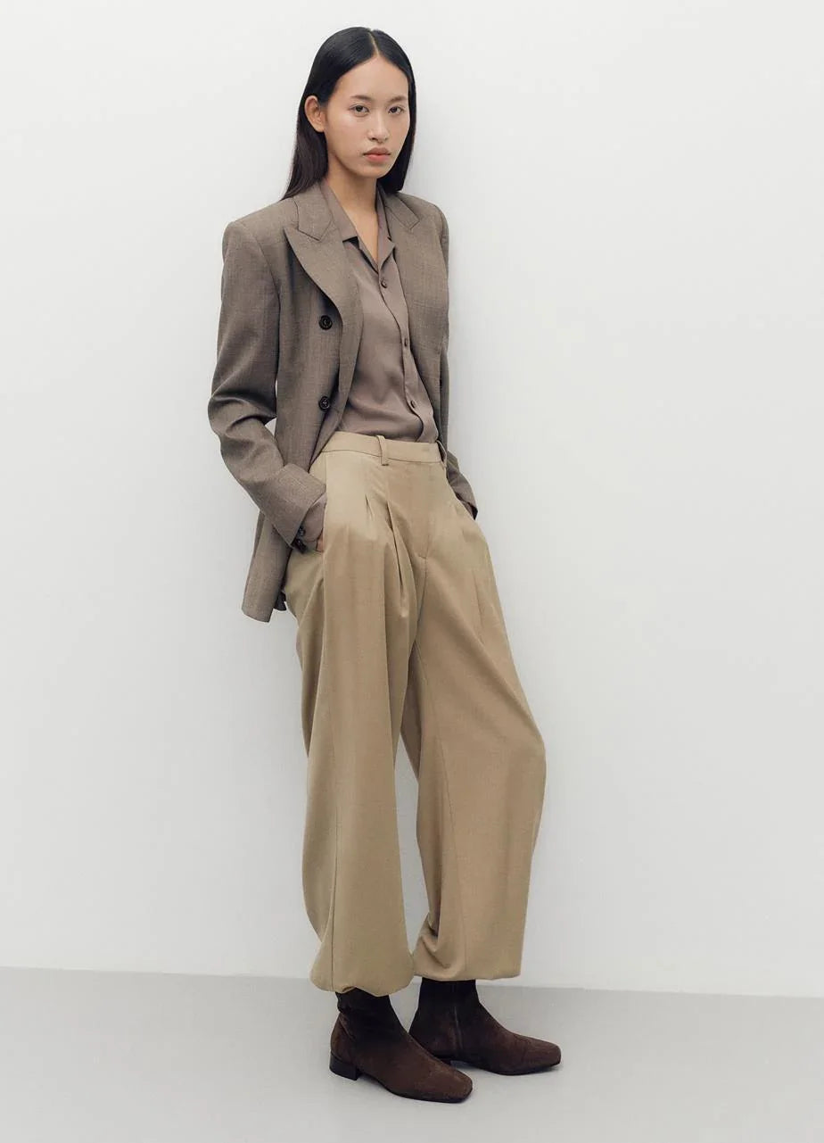 אישה עומדת לובשת בלייזר חום, חולצה מכופתרת ומכנסיים רחבים, אופנה אלגנטית CHOZEN