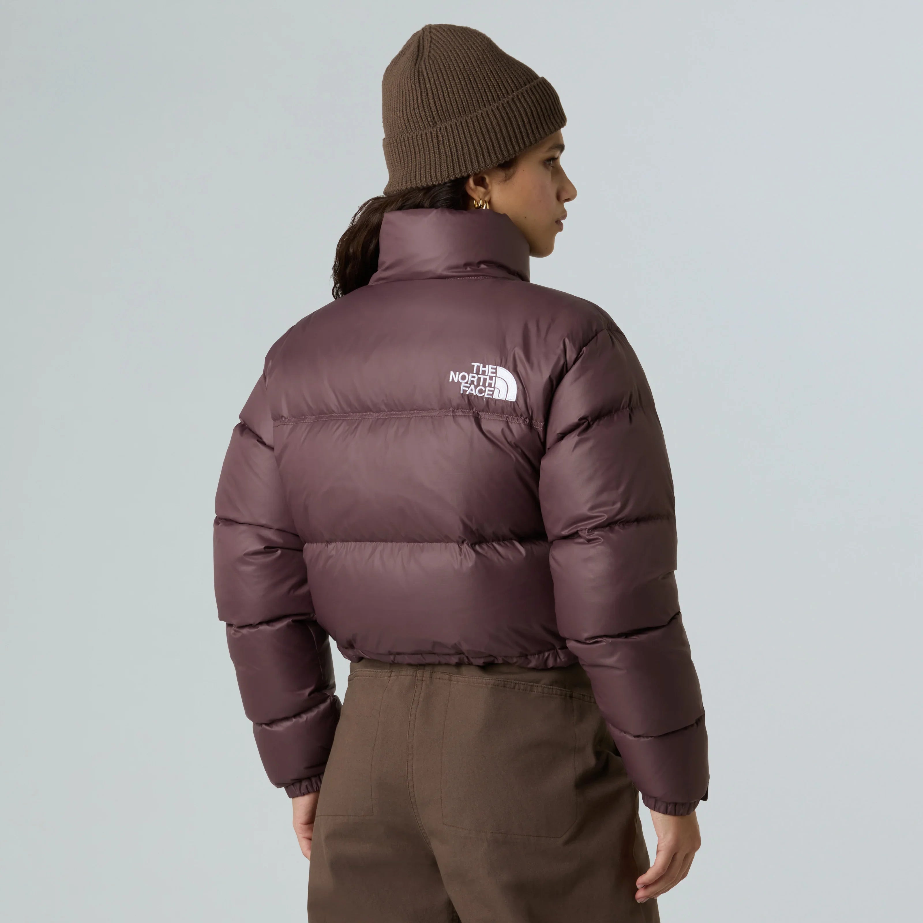 אישה עם מעיל פוך חום The North Face וכובע סרוג חום, בגדי חורף מותג מוביל CHOZEN