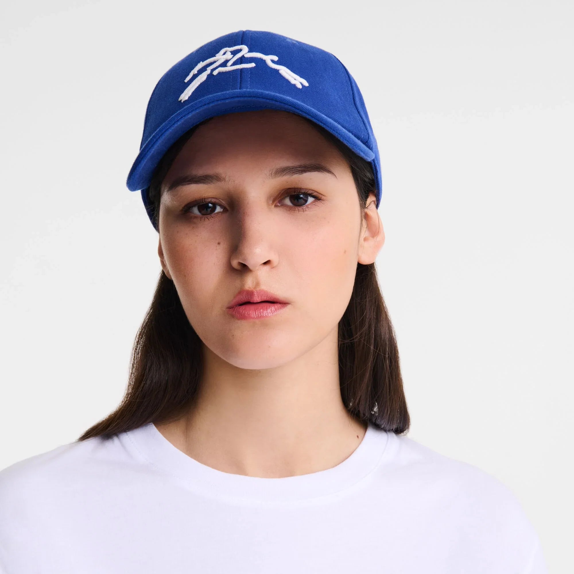 אישה עם כובע כחול ממותג CHOZEN וחולצה לבנה, רקע לבן