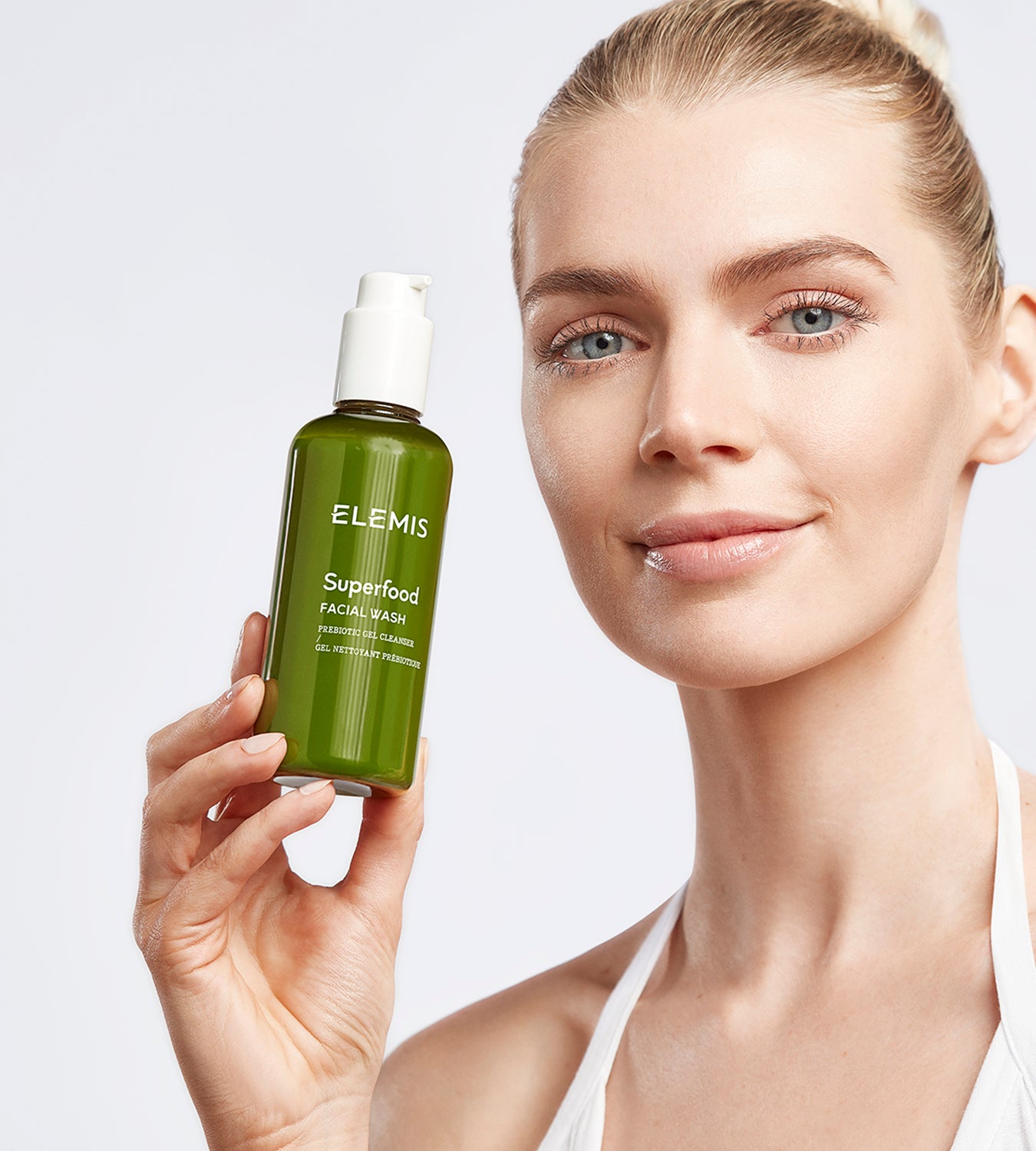 אישה מחזיקה ג'ל ניקוי לפנים ELEMIS Superfood, מוצר טיפוח מקצועי, רקע לבן