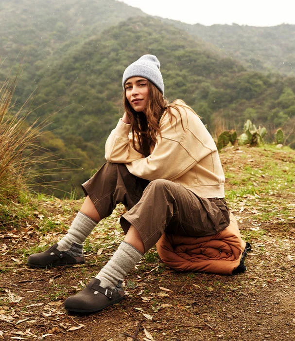 אישה בלבוש חורפי יושבת בטבע, נעלי בירקנשטוק, חווית אופנה CHOZEN