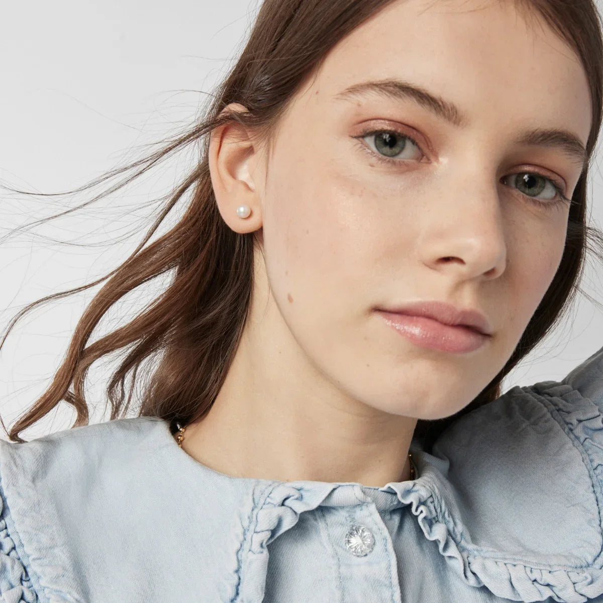 אישה צעירה עם חולצה כחולה בהירה, עגיל פנינה בולט, צילום תקריב, CHOZEN מותגים מובילים