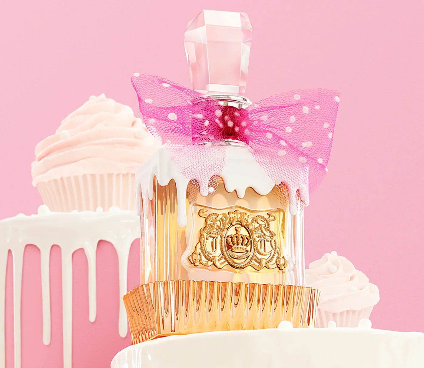 בקבוק בושם יוקרתי עם סרט ורוד, רקע ורוד וקאפקייקס בציפוי לבן