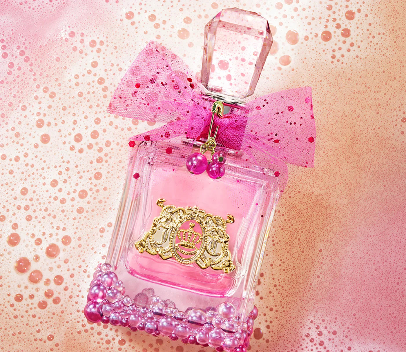 בקבוק בושם יוקרתי ורוד עם פקק קריסטלי, קישוט סרט ורוד ורקע בועות ורודות