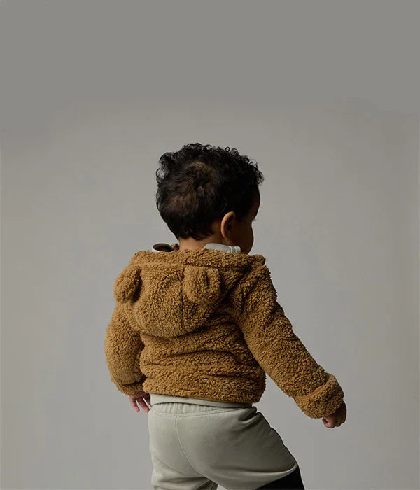 פעוט לובש קפוצ׳ון דובי חום של CHOZEN על רקע סטודיו ניטרלי