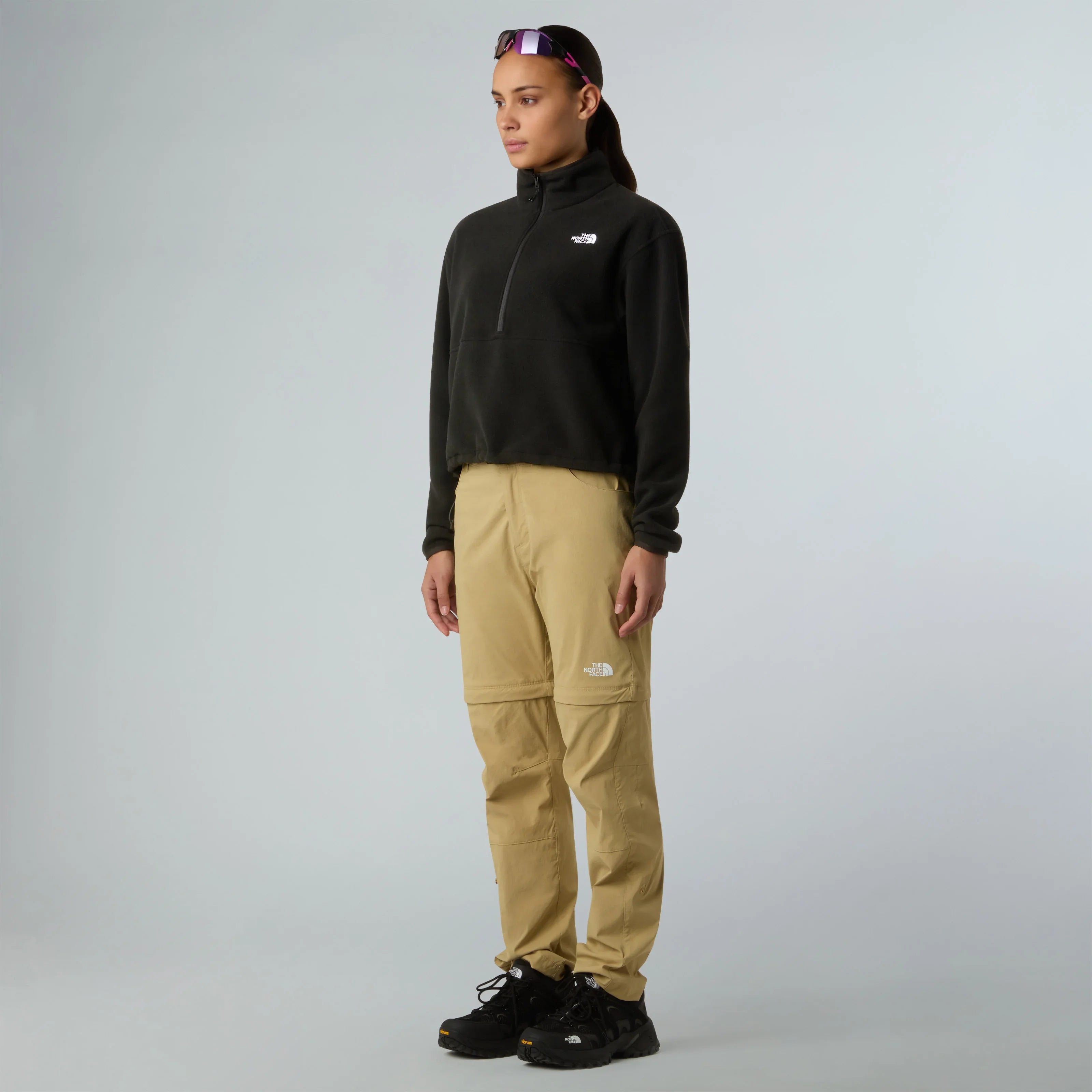 אישה לובשת בגדי נורת' פייס, סווטשרט שחור ומכנסי בז', רקע לבן, CHOZEN מותגים מובילים