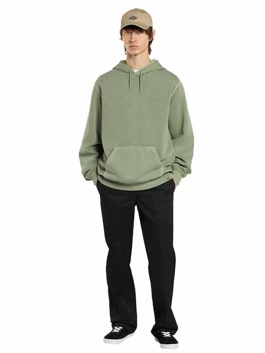 דגם גבר לבוש בקפוצ'ון ירוק, מכנסיים שחורים, כובע בז', ונעלי סניקרס, אופנת רחוב CHOZEN