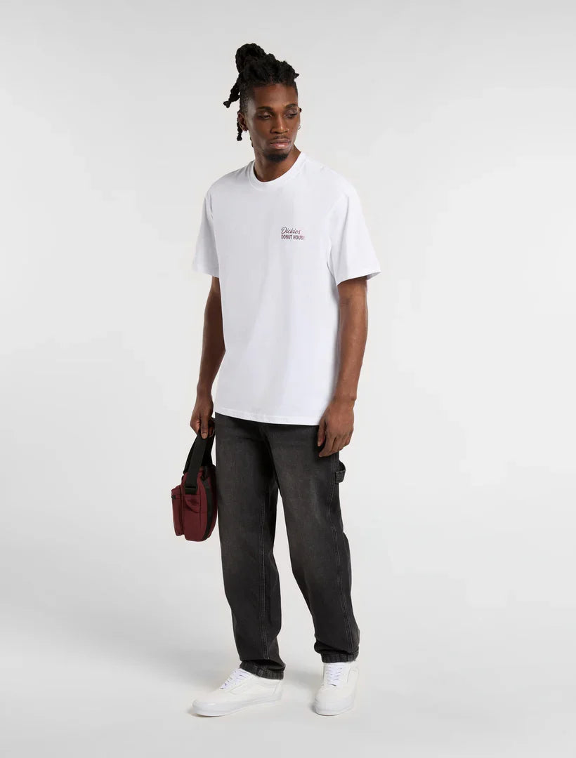 גבר לובש חולצת טי לבנה של Dickies, מכנסי ג'ינס כהים ונעליים לבנות, מחזיק תיק אדום בסטייל אופנתי CHOZEN