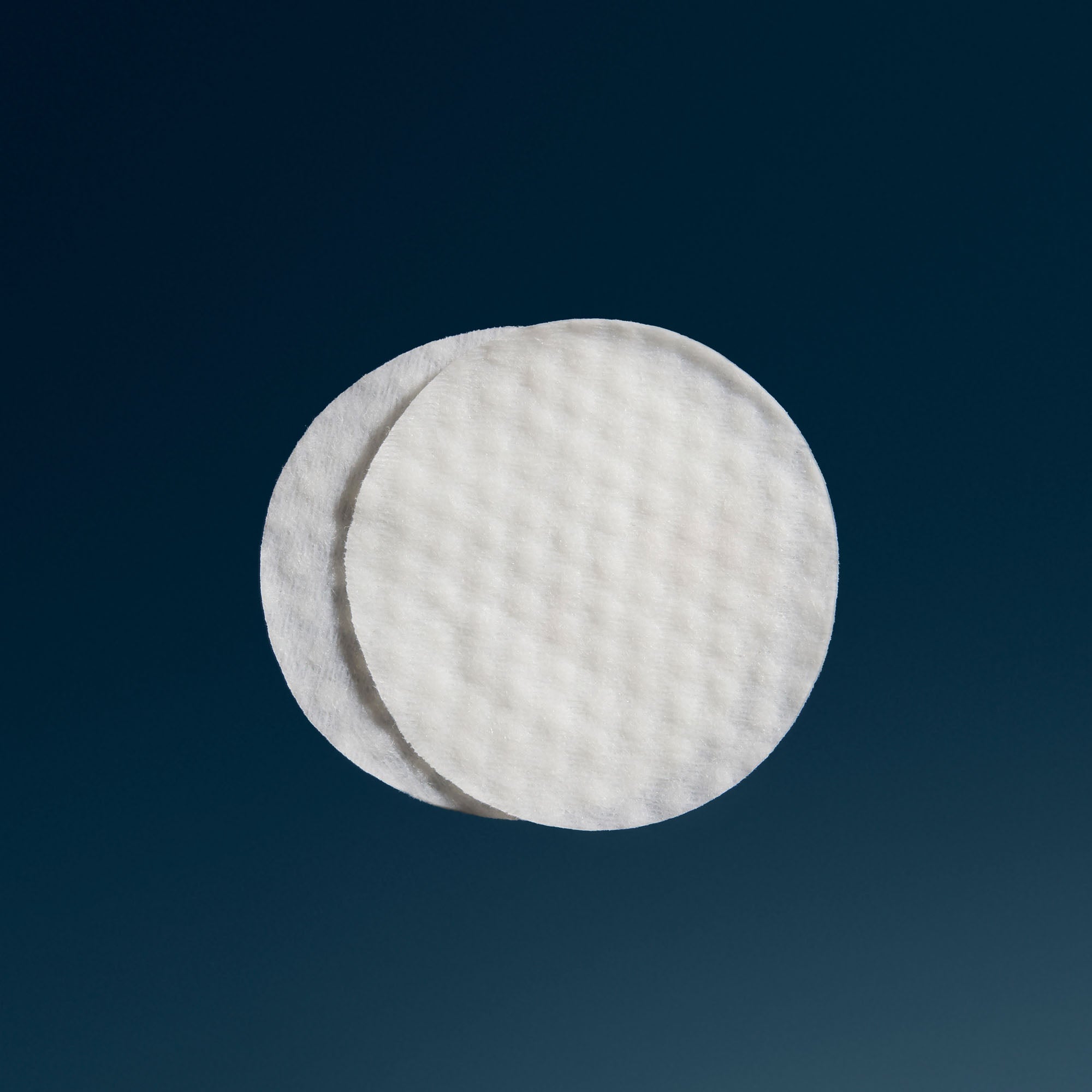 פדים עגולים לניקוי והחלקת עור הפנים, מרקם עדין על רקע כהה