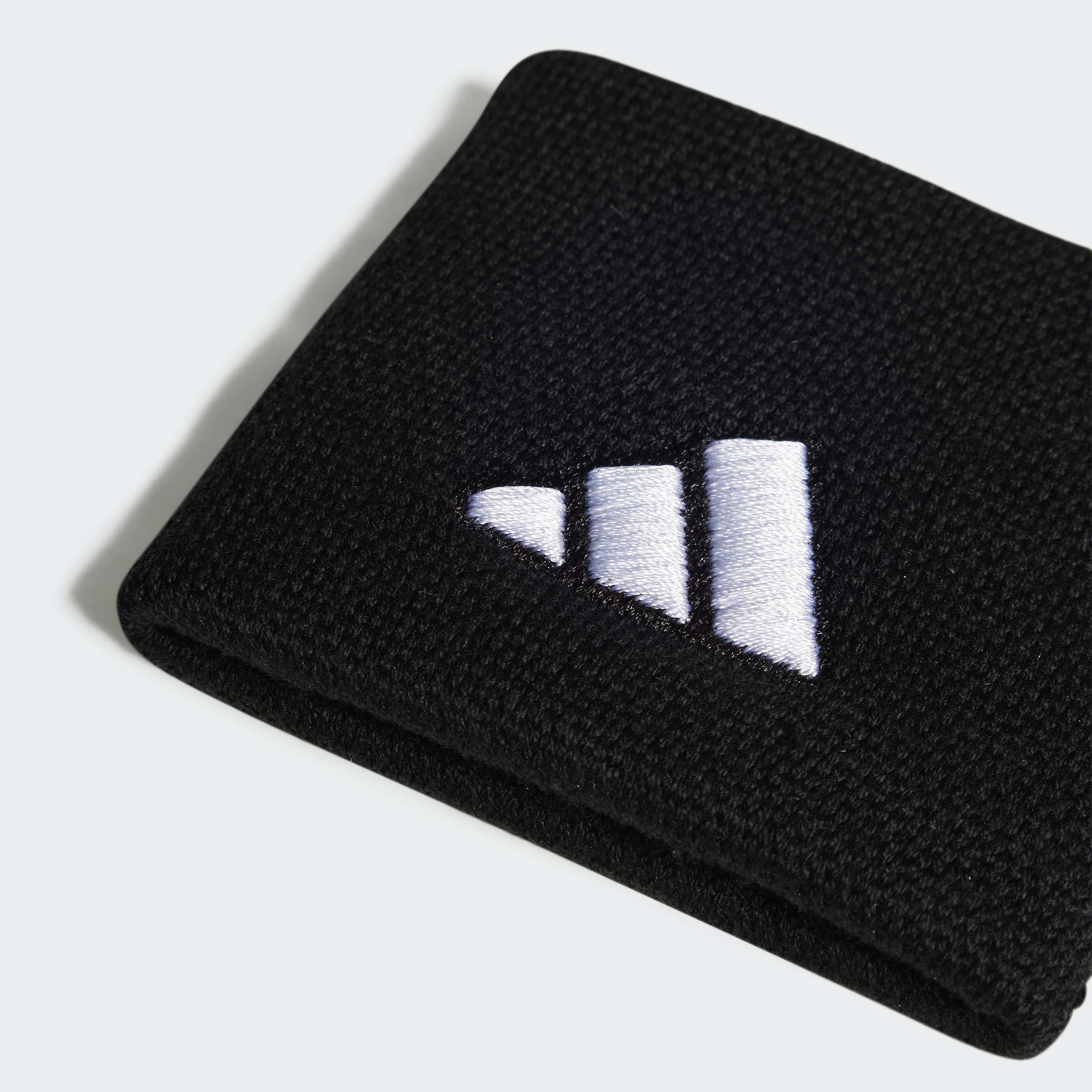 סרט ספורט אלסטי בצבע שחור עם לוגו רקום בלבן, צילום תקריב על רקע בהיר