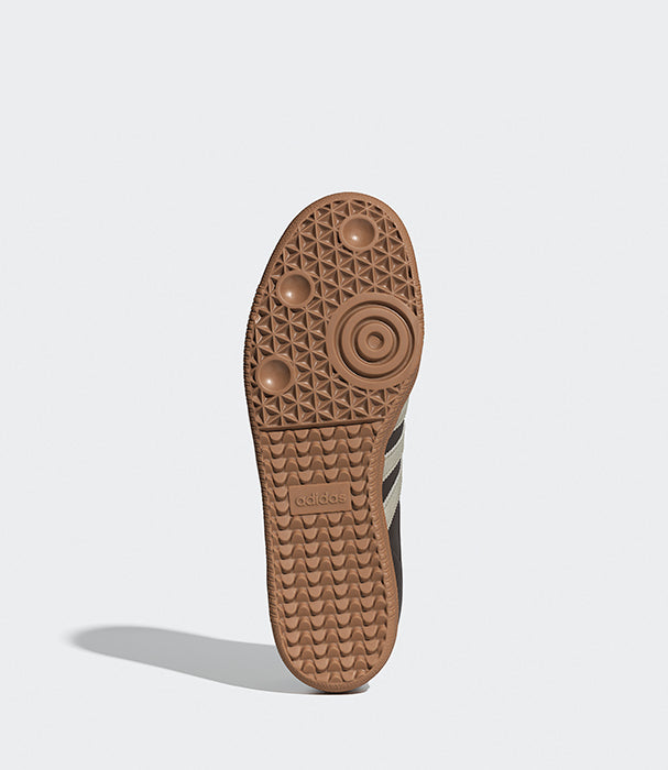 תחתית סוליית נעל ספורט בצבע חום עם דוגמה גיאומטרית, רקע אפור.