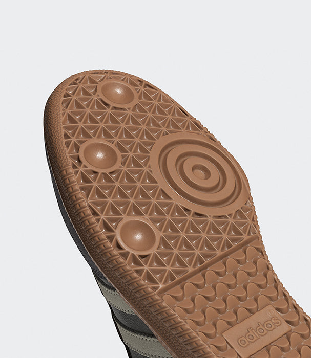 תקריב סוליית נעל ספורט חומה עם דוגמה גאומטרית ופסים שחורים בצדדים