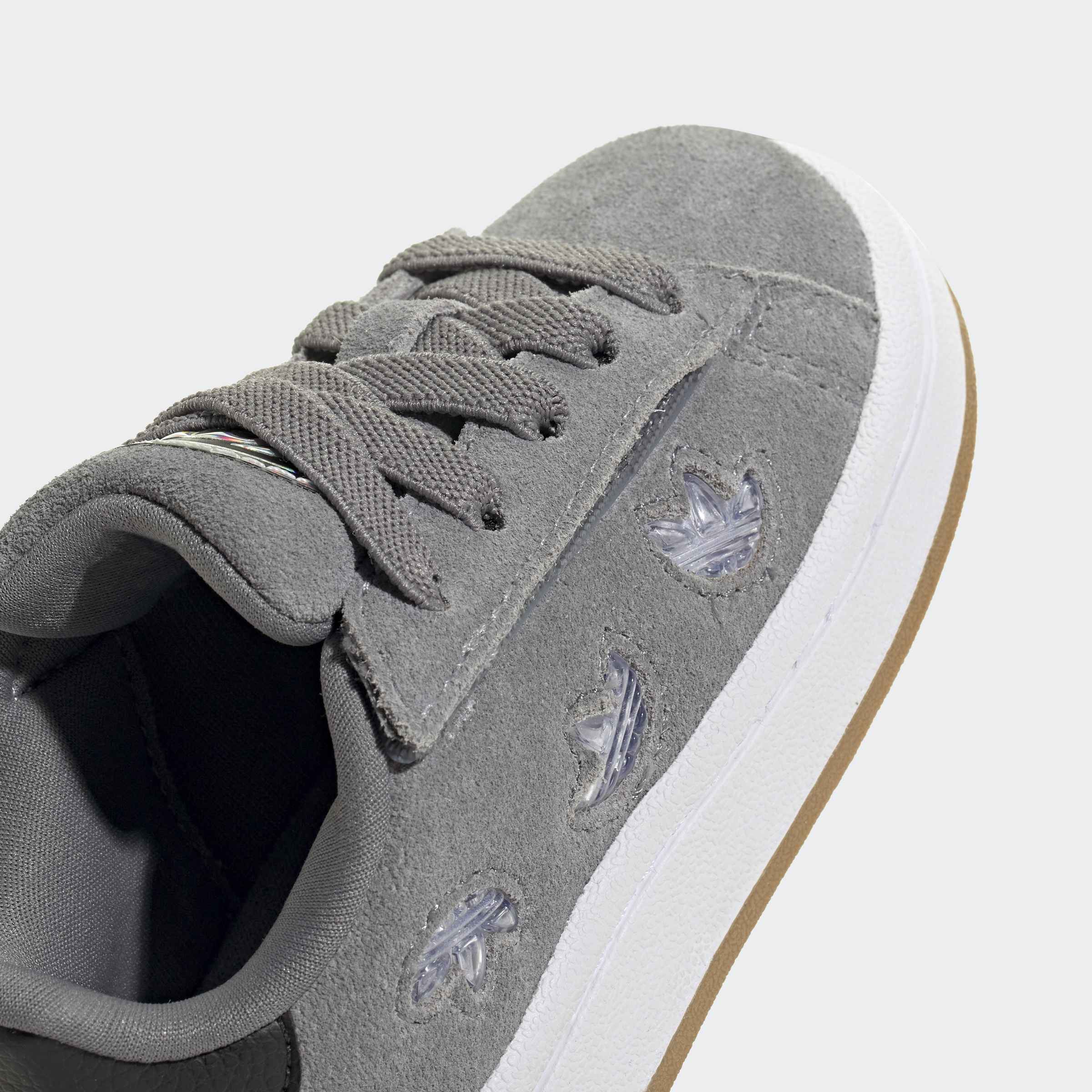 נעל ספורט אפורה מזמש עם שרוכים, סוליה לבנה ודיטיילים שקופים בצד