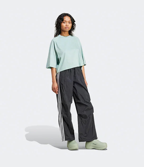 אופנה ספורטיבית ב-CHOZEN: דוגמנית לובשת חולצה רחבה ירוקה, מכנסי ספורט שחורים עם פסי צד ונעליים ירוקות