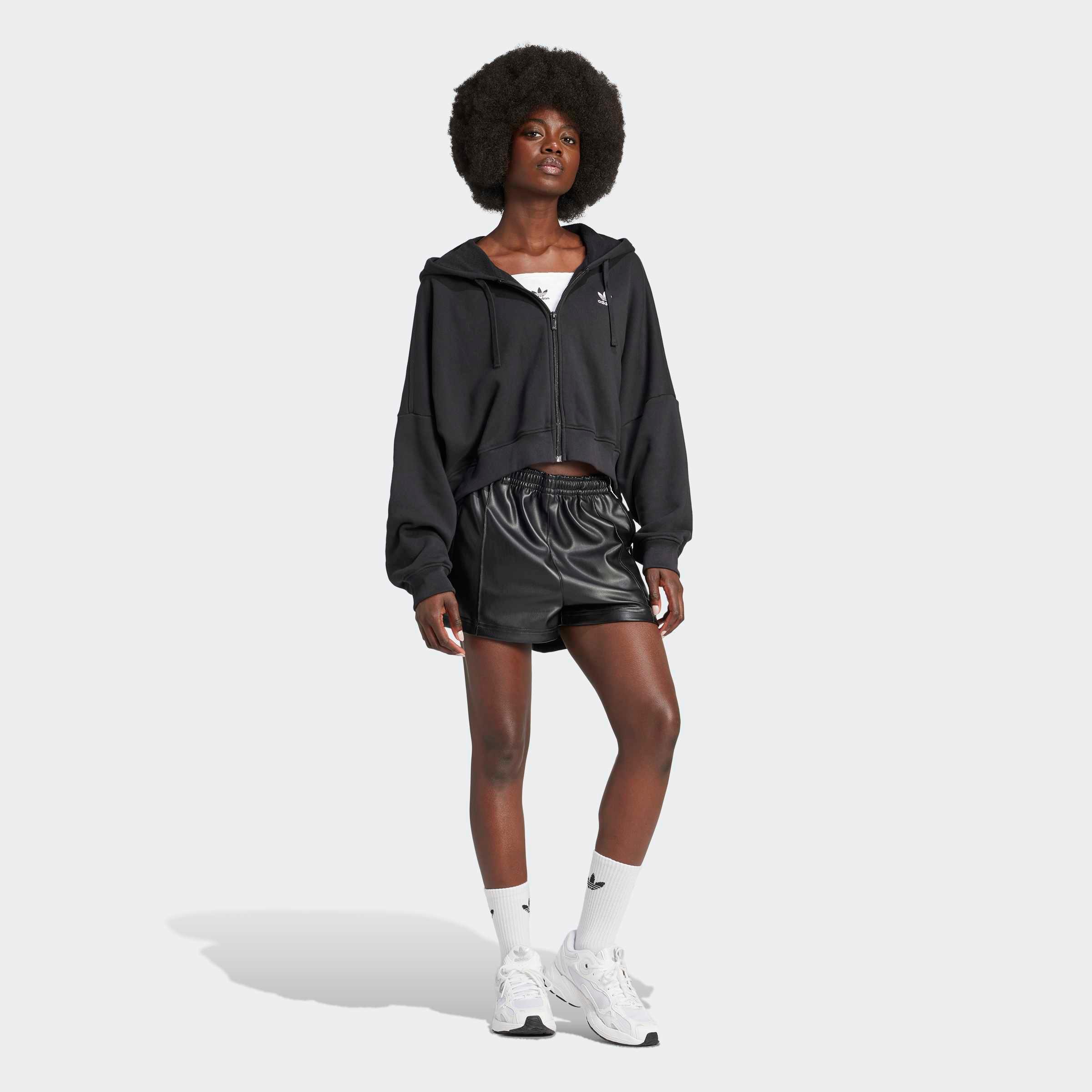 דוגמנית לובשת ג'קט שחור, מכנסי ספורט קצרים ונעלי סניקרס לבנות, אופנת רחוב CHOZEN