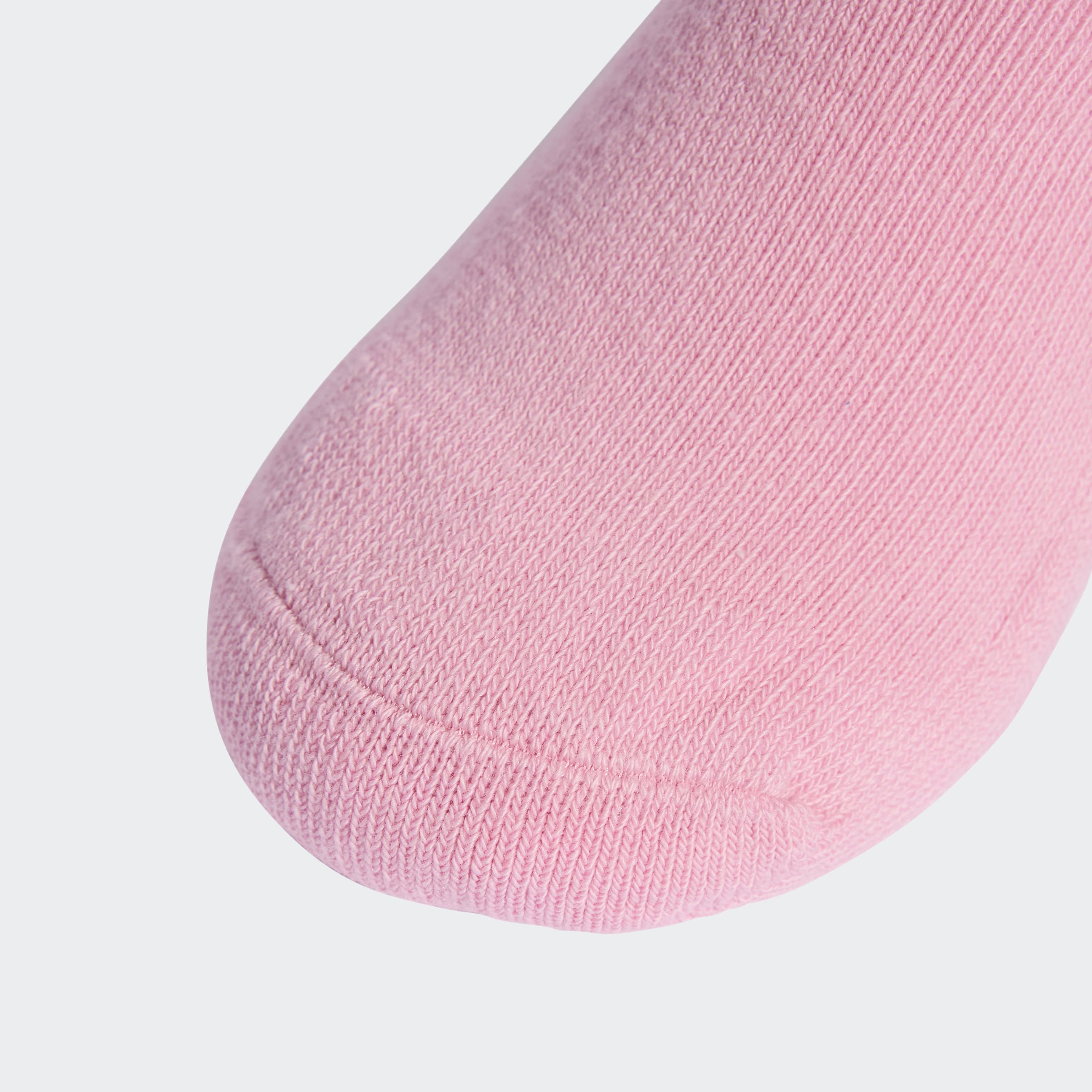 קלוז אפ של קצה גרב ורודה מבד כותנה על רקע אפור