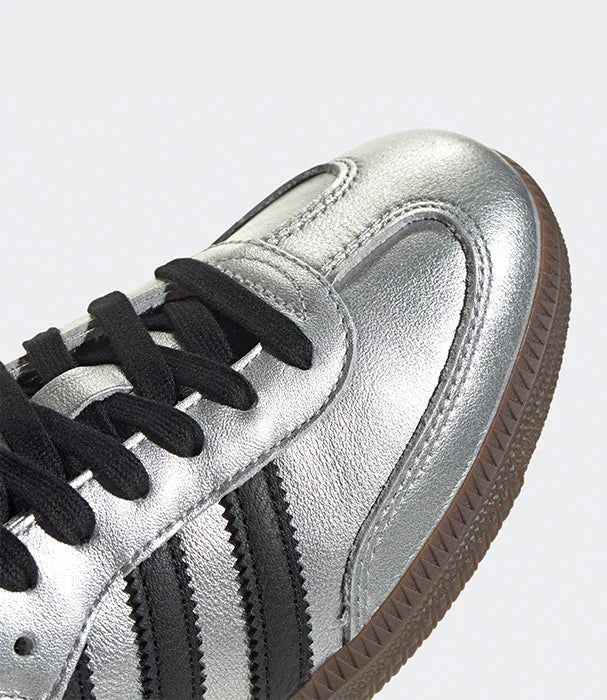 נעל ספורט כסופה עם פסי שחור, שרוכים שחורים וסוליה חומה, בחנות CHOZEN