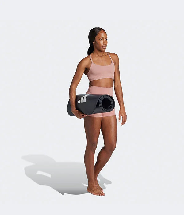 אישה לובשת סט ספורט ורוד עם שטיח יוגה שחור, צילום לקטלוג CHOZEN