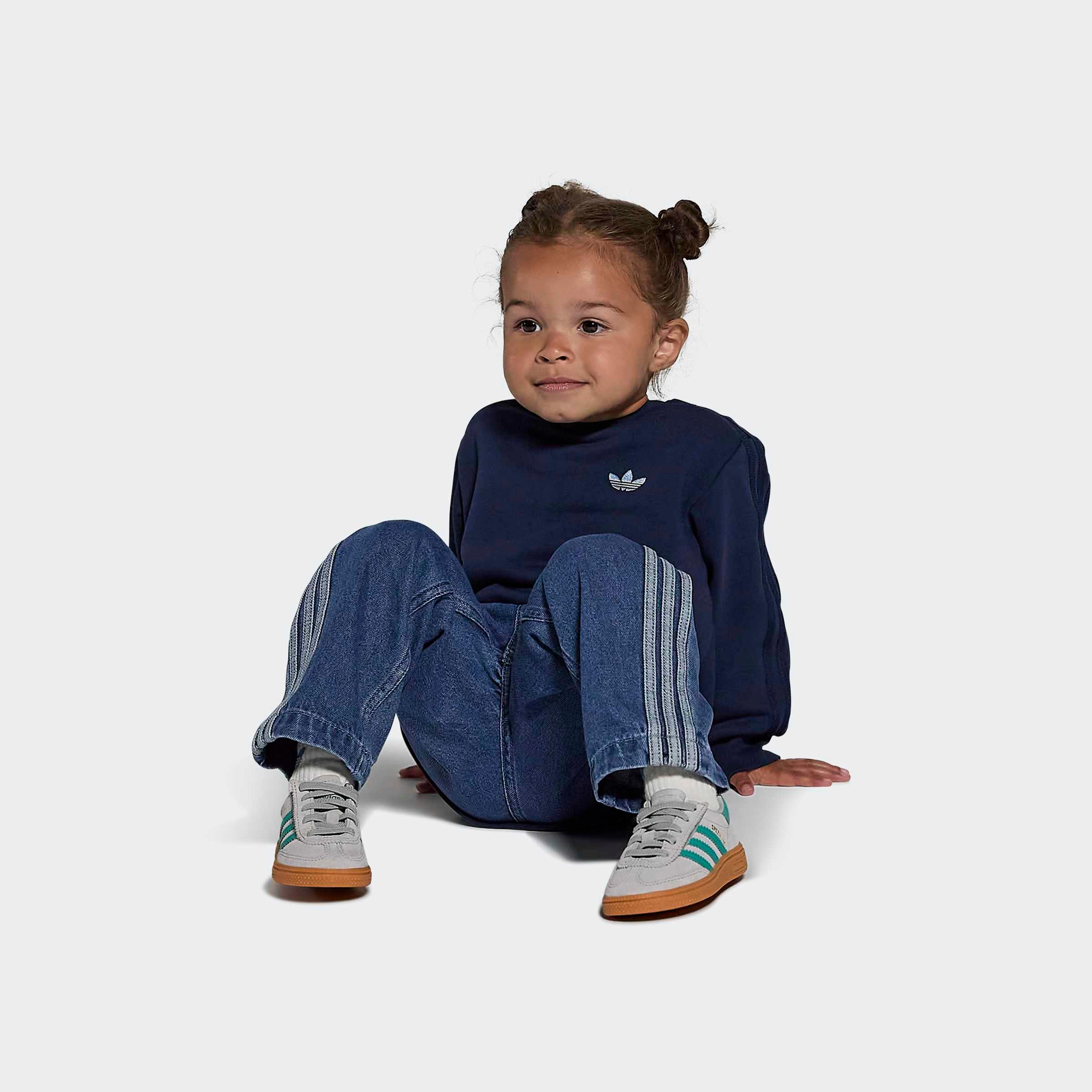 ילד לובש נעלי ספורט אפורות עם פסים ירוקים, חולצת טרנינג כחולה ומכנסי ג'ינס, על רקע לבן, CHOZEN