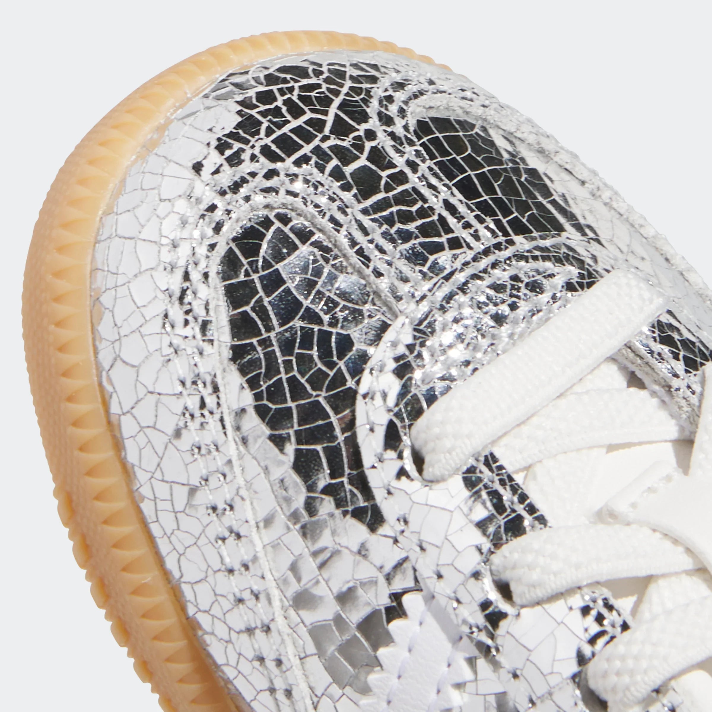 תקריב על נעל סניקרס עם דוגמת כסף סדוקה, שרוכים לבנים וסוליה בהירה