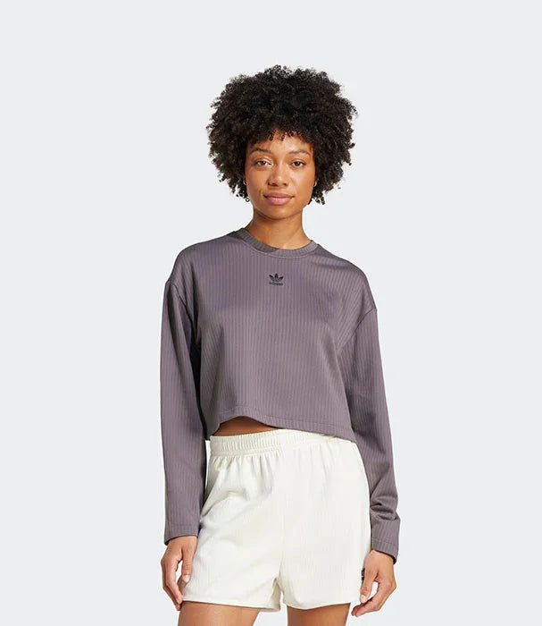 דגם של אישה לובשת חולצת אדידס אפורה עם שרוולים ארוכים ומכנסיים קצרים לבנים, CHOZEN