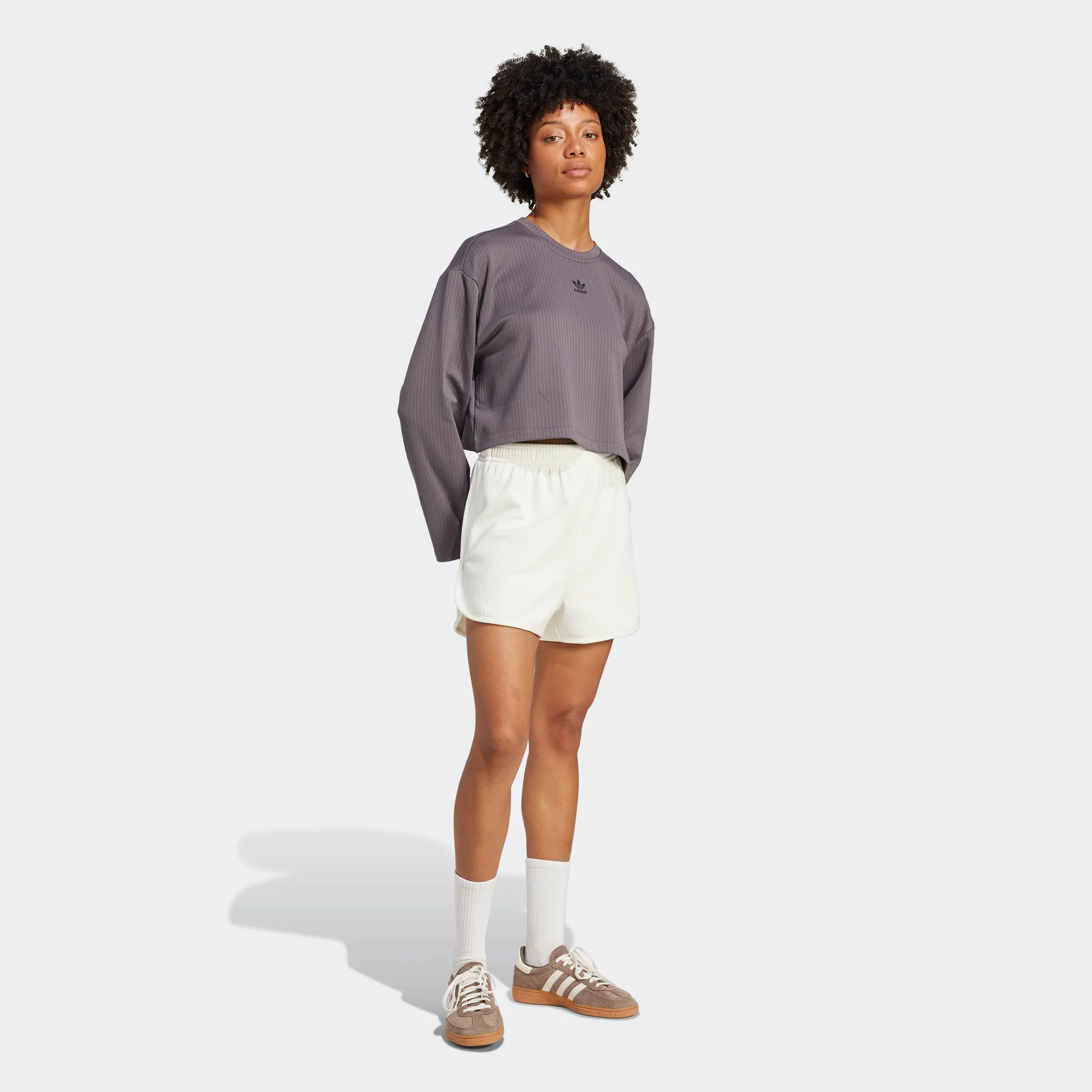 אופנת נשים CHOZEN, דוגמנית עם חולצה אפורה, מכנסיים קצרים בהירים ונעלי אדידס