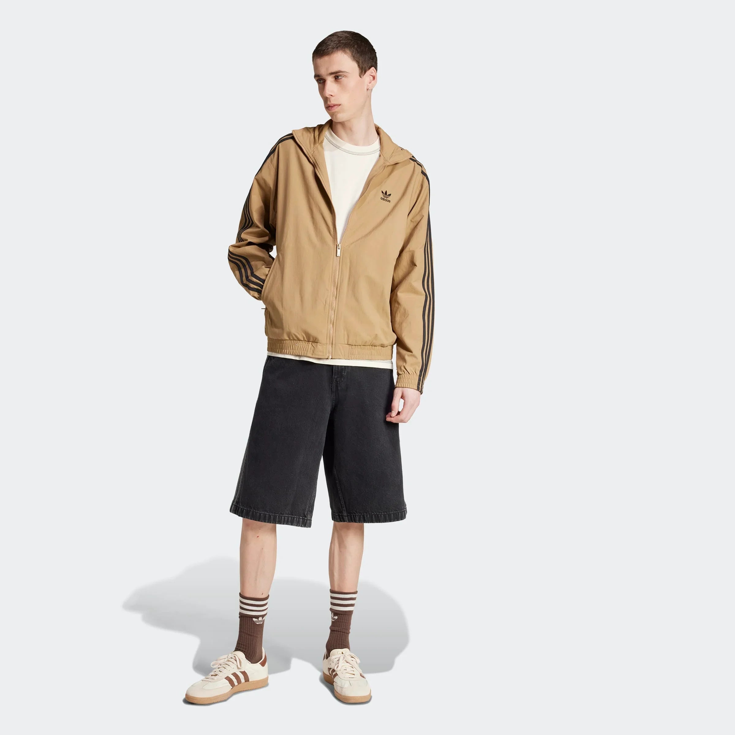 דגם גבר לובש ג'קט אדידס בז', מכנסי ברמודה שחורות, נעלי סניקרס, ב-CHOZEN מותגים מובילים