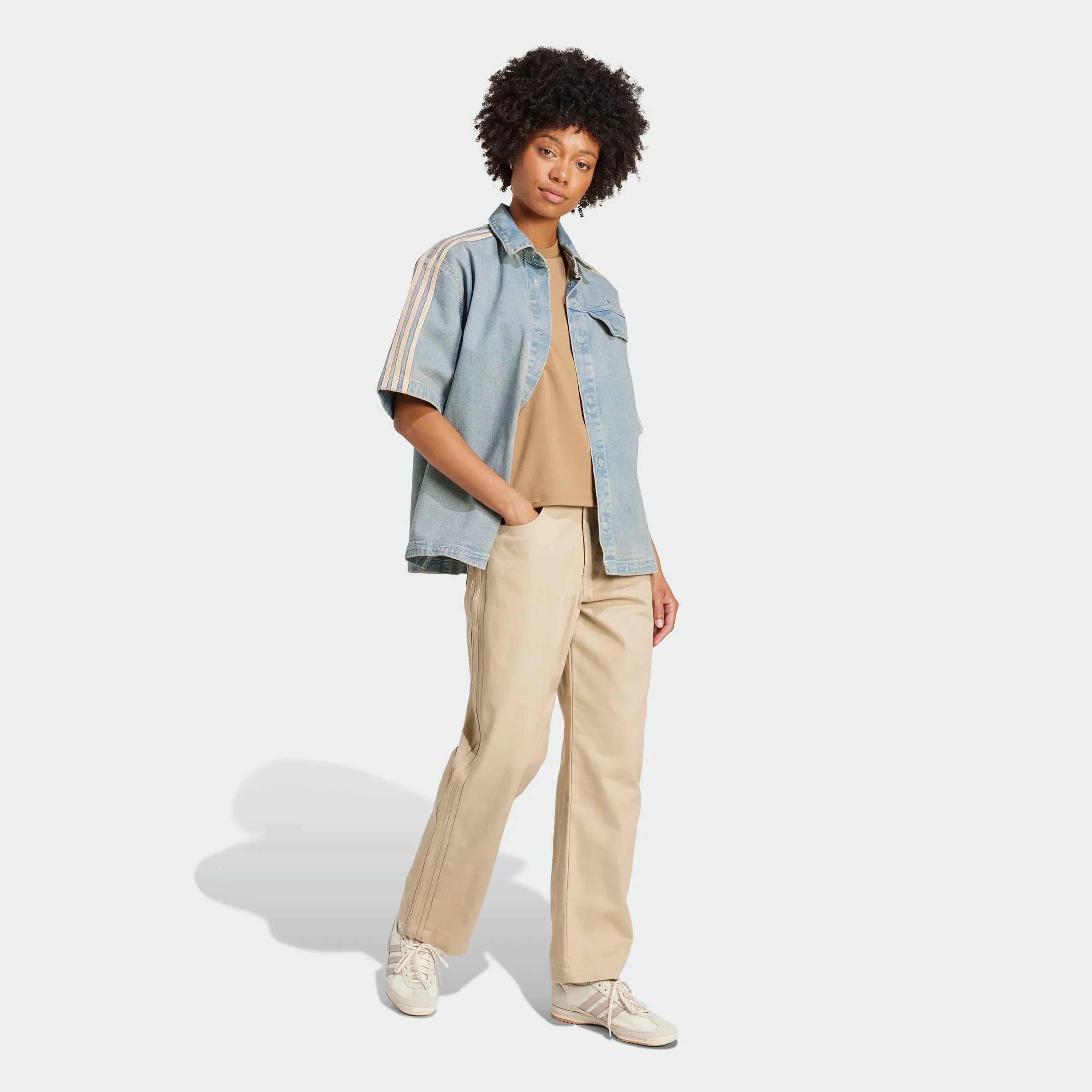 אישה מדגמנת בגדי קז'ואל אופנתיים של CHOZEN, חולצת ג'ינס ומכנסי בז', רקע לבן