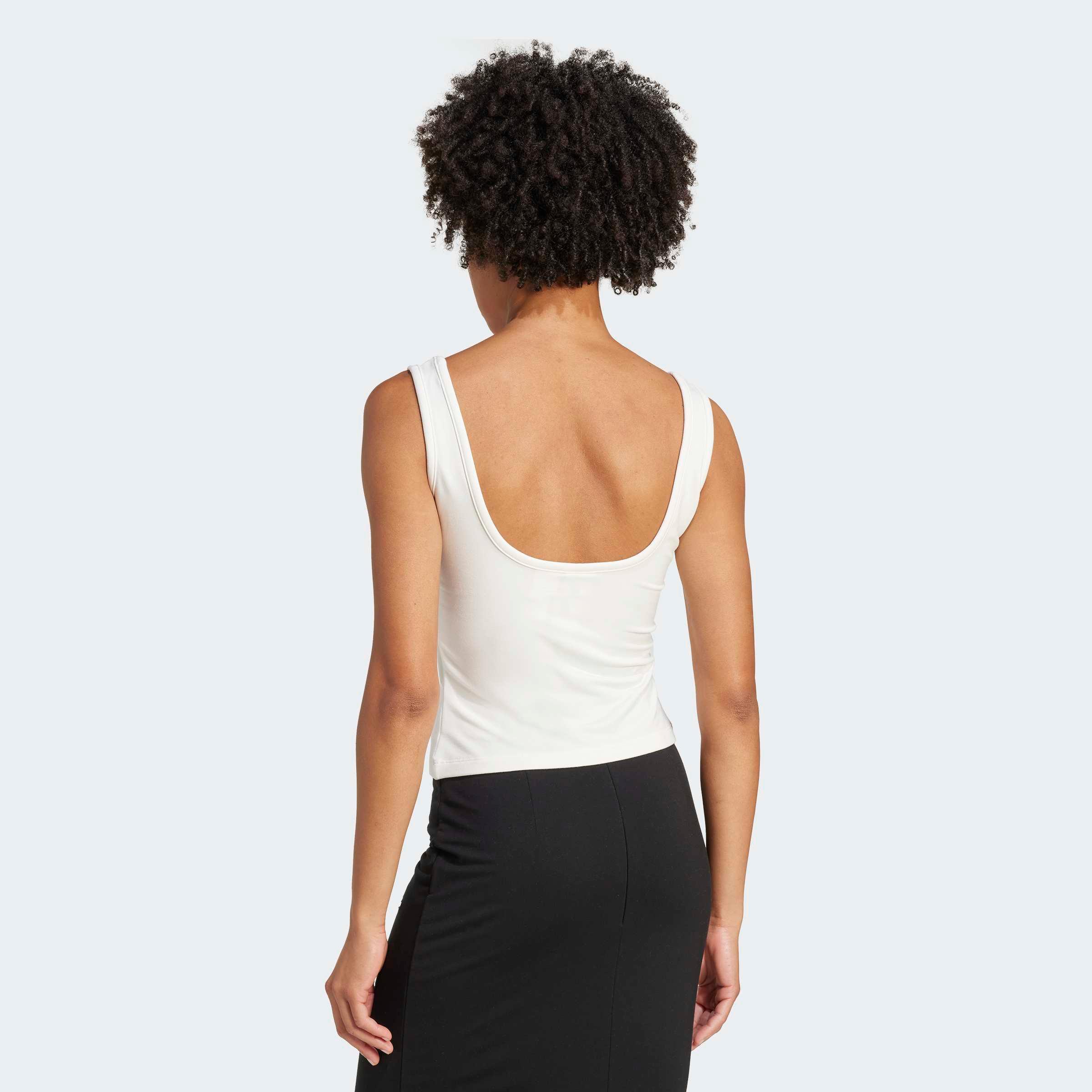 דוגמנית בגב חשוף לובשת גופייה לבנה וחצאית שחורה, אופנה לנשים ב-CHOZEN