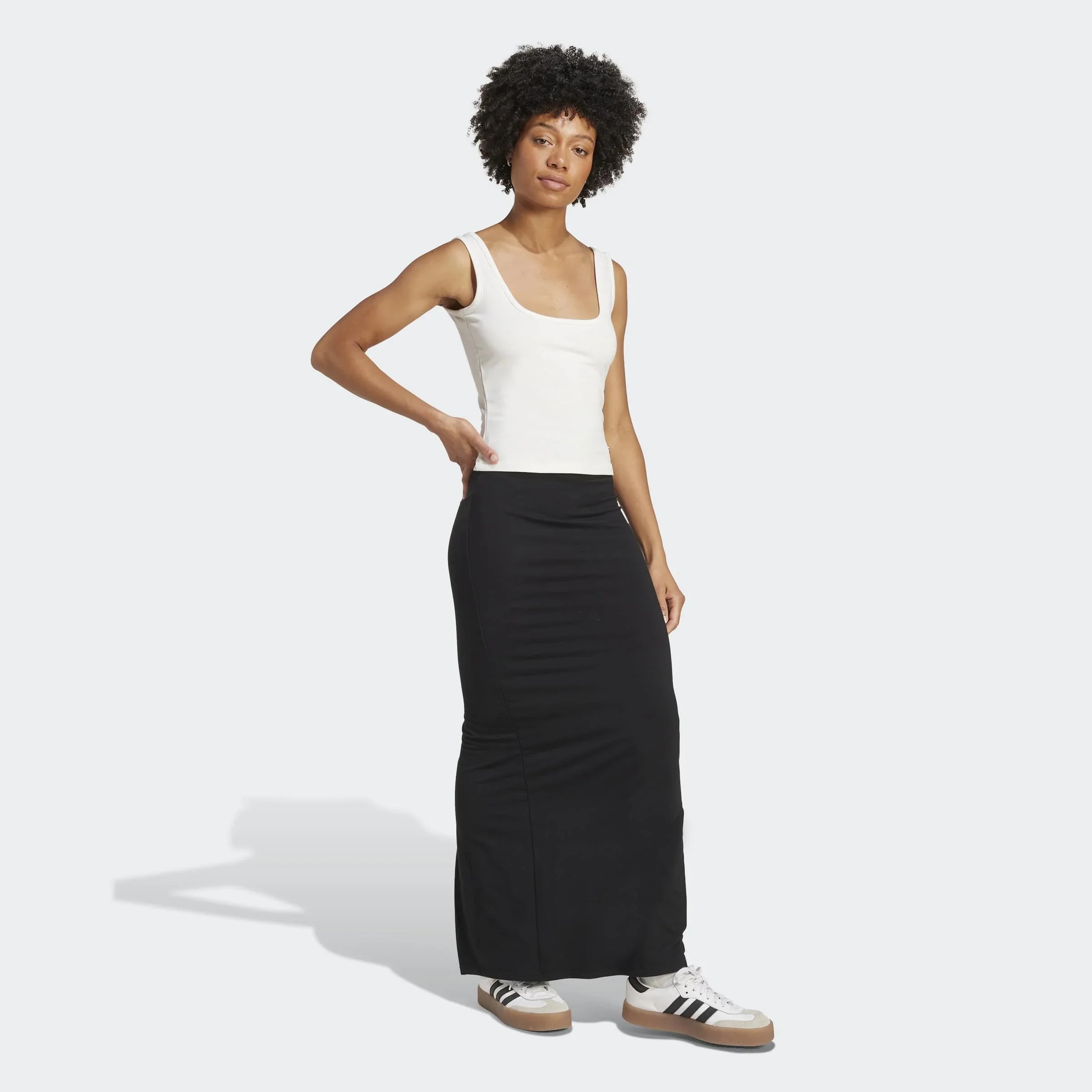 אישה עם טופ לבן וחצאית שחורה, נעלי סניקרס אדידס, רקע לבן, CHOZEN אופנת קז'ואל