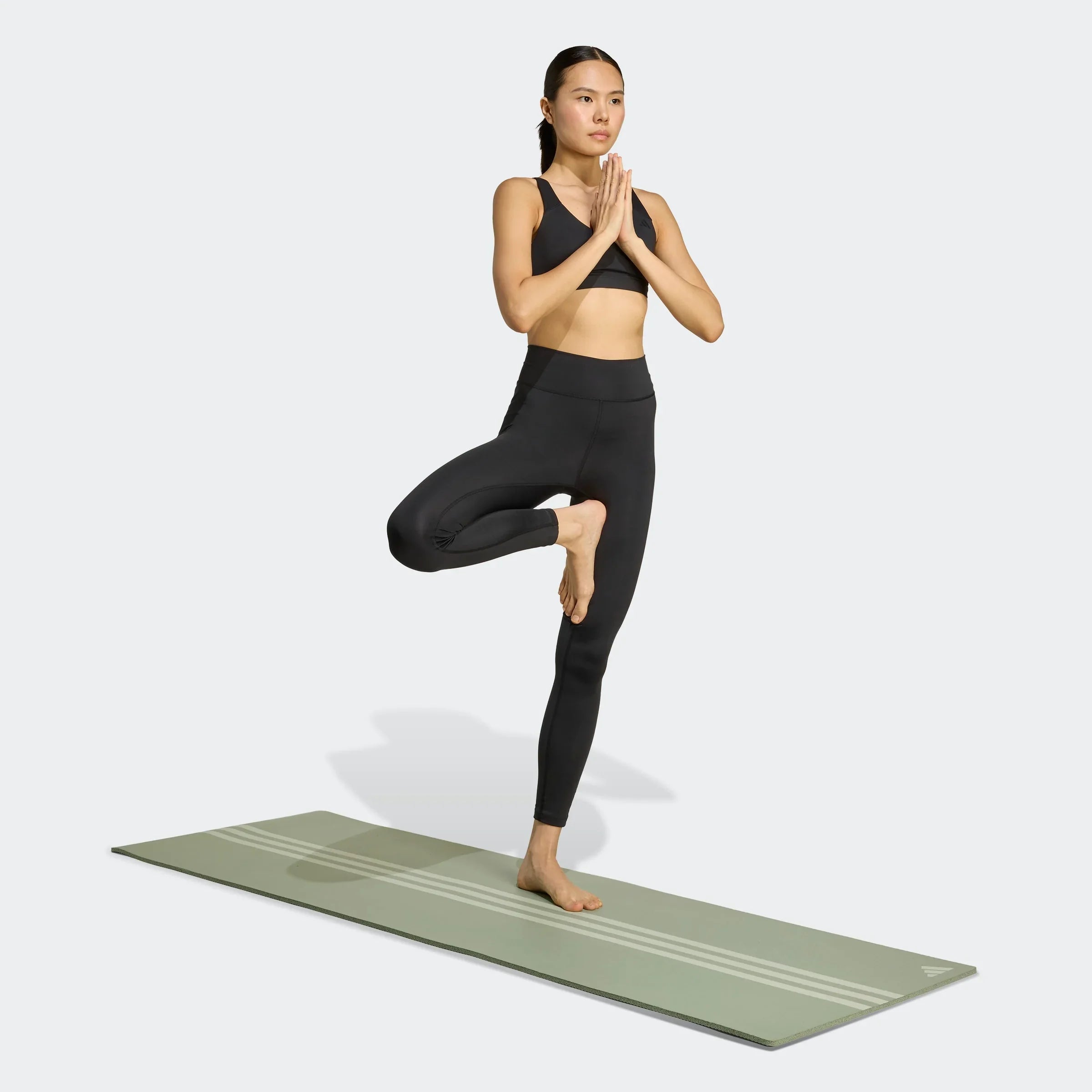 אישה בפעילות יוגה על מזרן, בגדי ספורט שחורים, צילום לאתר CHOZEN