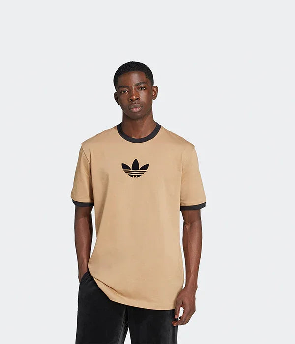 דגם לובש חולצת אדידס בז׳ עם לוגו שחור, אופנת רחוב לגברים באתר CHOZEN