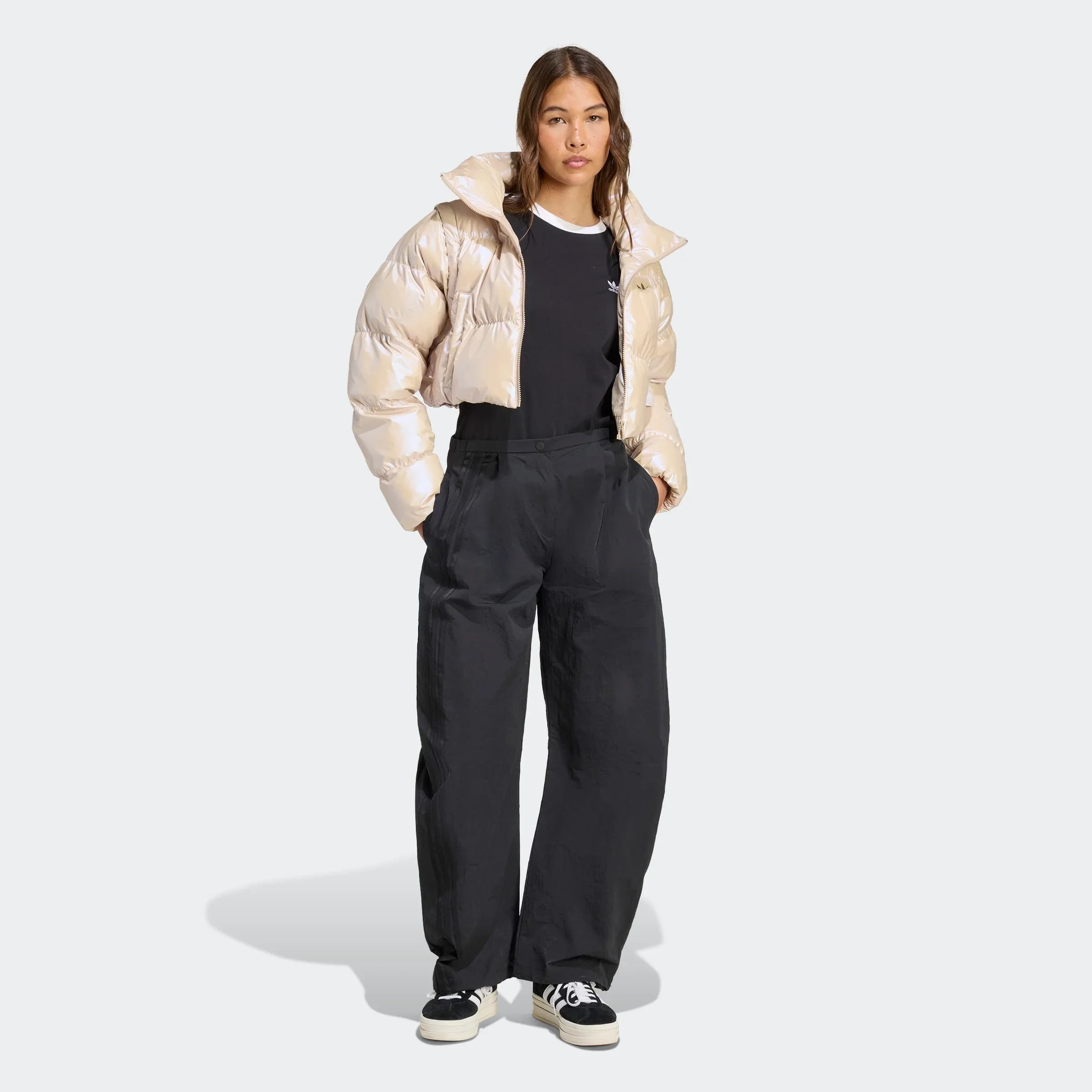 אישה לובשת ג׳קט פוך קצר בז׳, חולצה שחורה ומכנסיים רחבים שחורים מבית CHOZEN