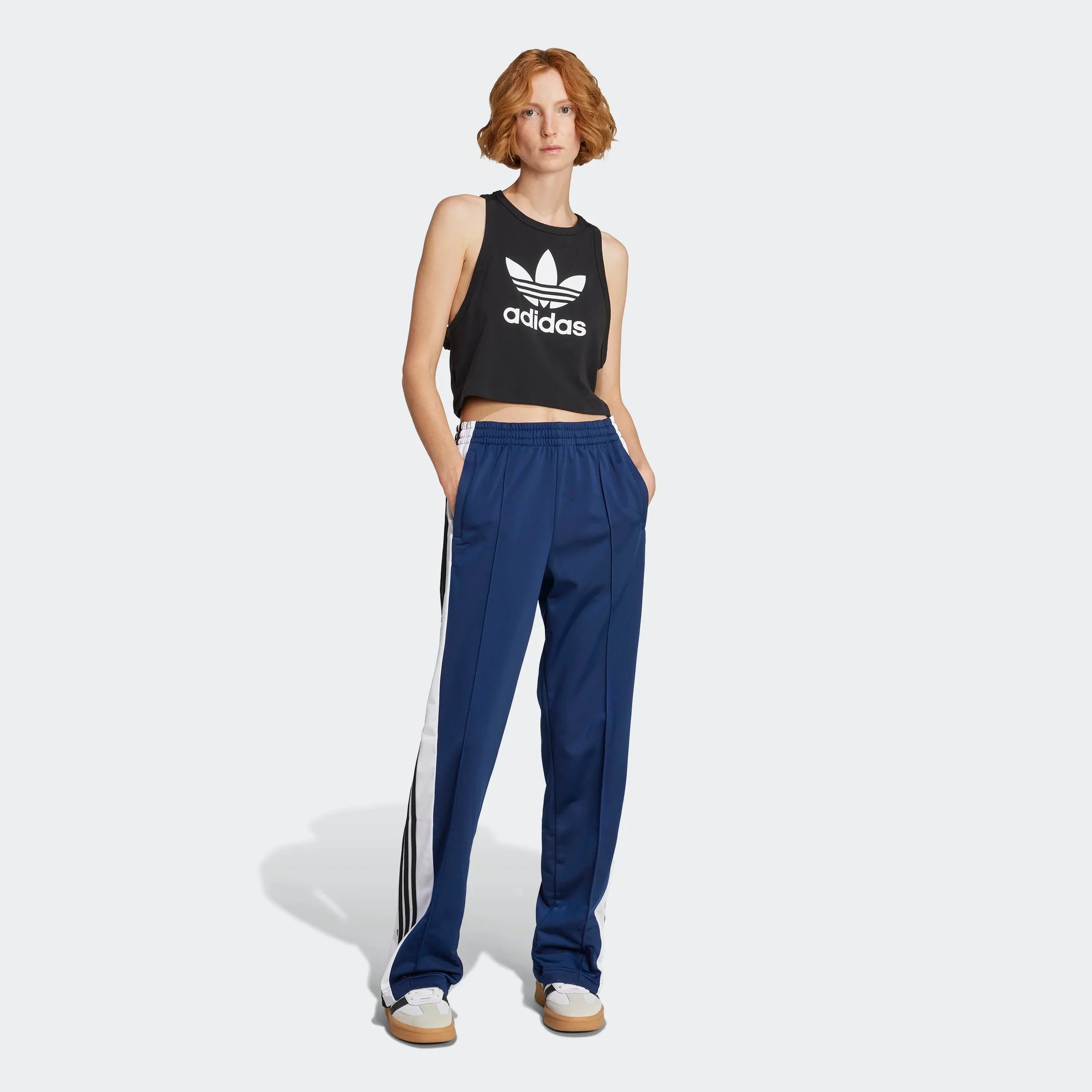 דוגמנית לובשת גופיית adidas שחורה עם לוגו ומכנסי טרנינג כחולים, אופנת ספורט CHOZEN