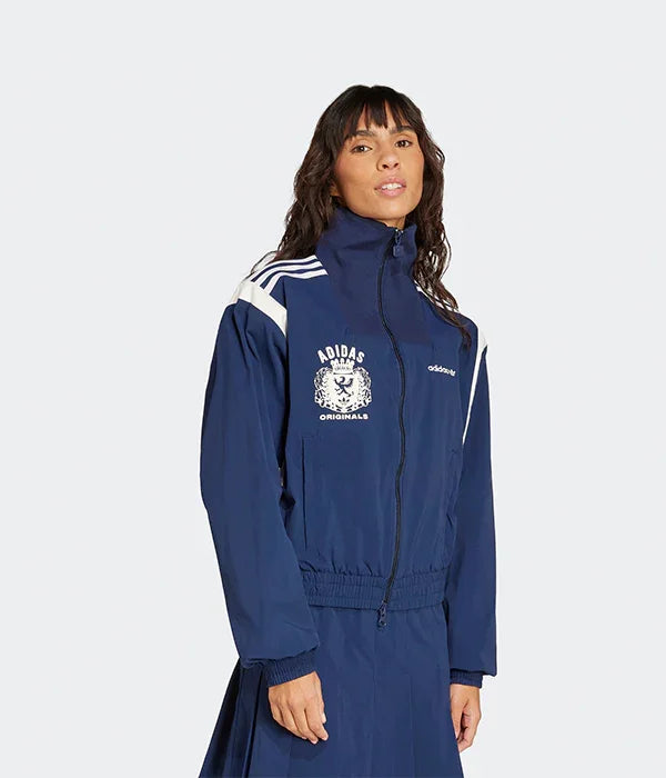 אישה מדגמנת ז'קט אדידס כחול עם לוגו לבן, בגדי מותגים מבית קבוצת אלפא CHOZEN