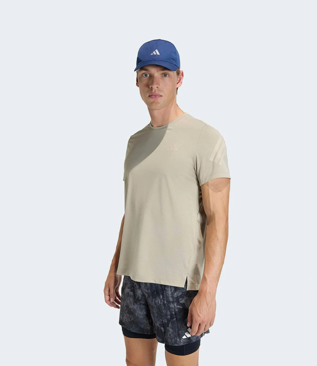 דוגמן לובש חולצת טי אפורה, כובע כחול ומכנסי ריצה שחורים לגבר על רקע לבן